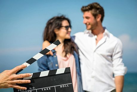 Man Hands Holding Movie Clapper In front of Cute Couple